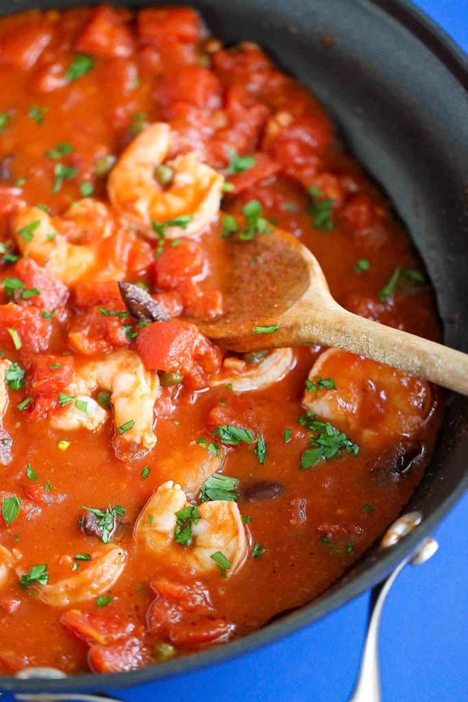 Shrimp cooking in a hearty puttanesca sauce.