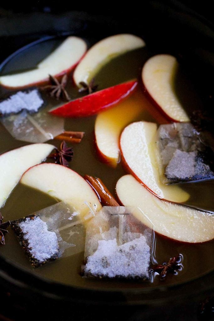 Apple slices, apple cider, star anise, cloves, cinnamon sticks and chai tea bags in a slow cooker.