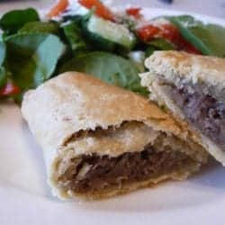 Jamaican meat patties and a salad on a white plate.