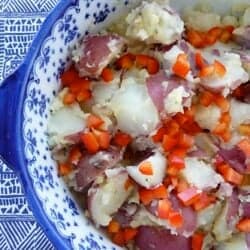 Potato salad with bell pepper in a blue and white bowl.