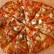Pizza with peanut sauce and vegetables, cut into wedges.