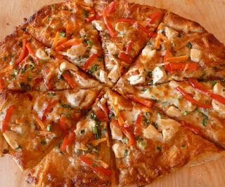 Pizza with peanut sauce and vegetables, cut into wedges.