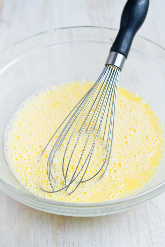 Whisked eggs and cottage cheese in a glass bowl