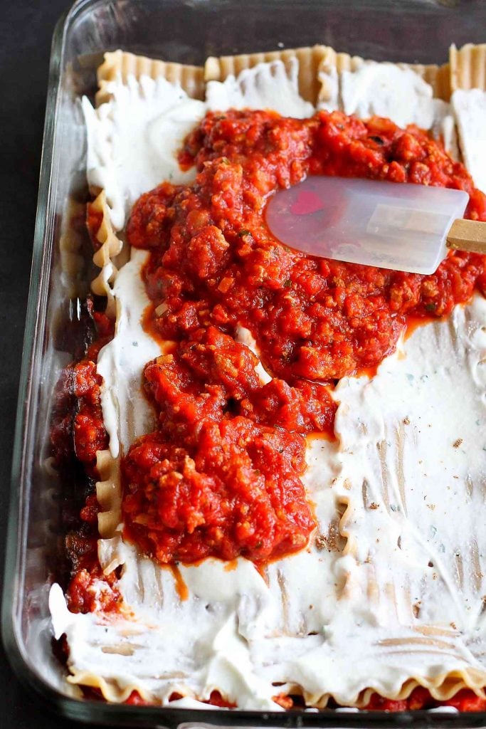 Layering lasagna noodles with marinara sauce