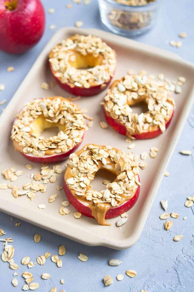 Apple slices topped with peanut and granola, on a small baking tray.