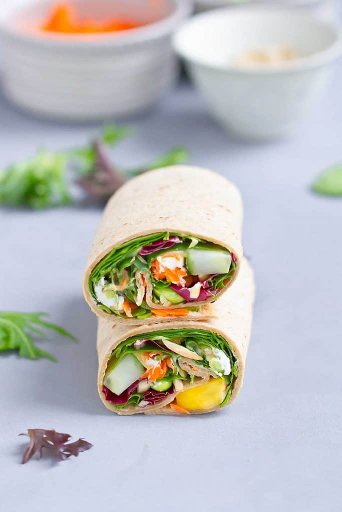 Up your lunch game with an Edamame Hummus Veggie Wrap. Packed with vegetables, goat cheese and mango, and drizzled with a simple hummus lemon dressing. 249 calories and 6 Weight Watchers SP | Lunches | Healthy | Easy | Tortilla | Cold | Meal Prep | Raw | Mediterranean | Vegetarian #lunchideas #healthylunches #veggiewrap #tortillawrap #wrapsandwich #smartpoints #weightwatchers