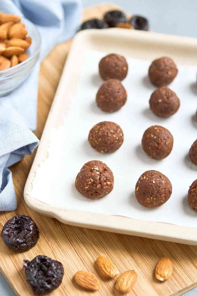 Prune almond protein balls on ceramic tray lined with parchment paper.