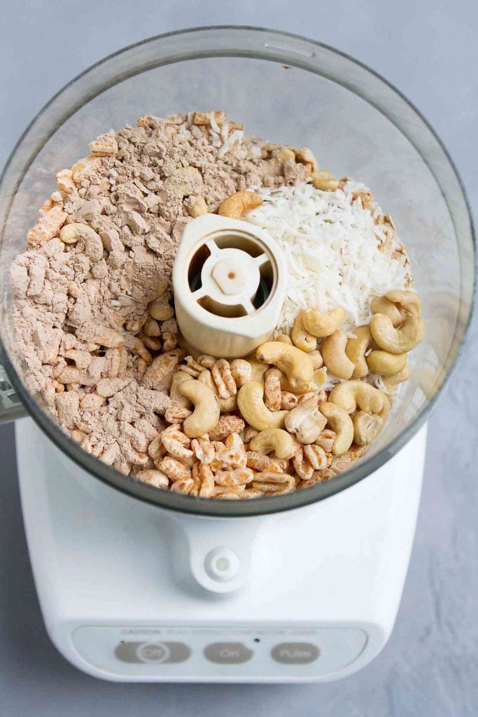 Oats, cashews, protein powder and coconut in a food processor