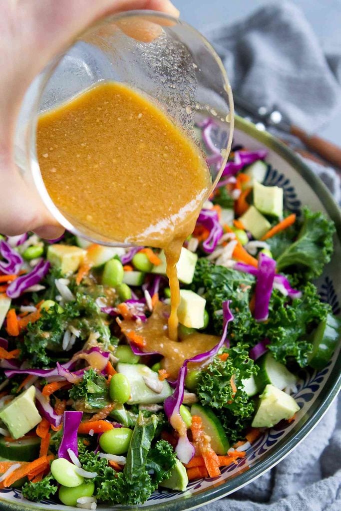 Pouring miso dressing over a superfood salad