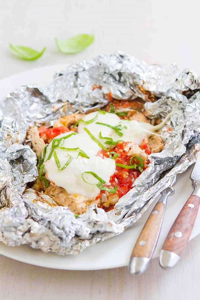 Chicken, topped with mozzarella cheese, tomatoes and basil in foil.