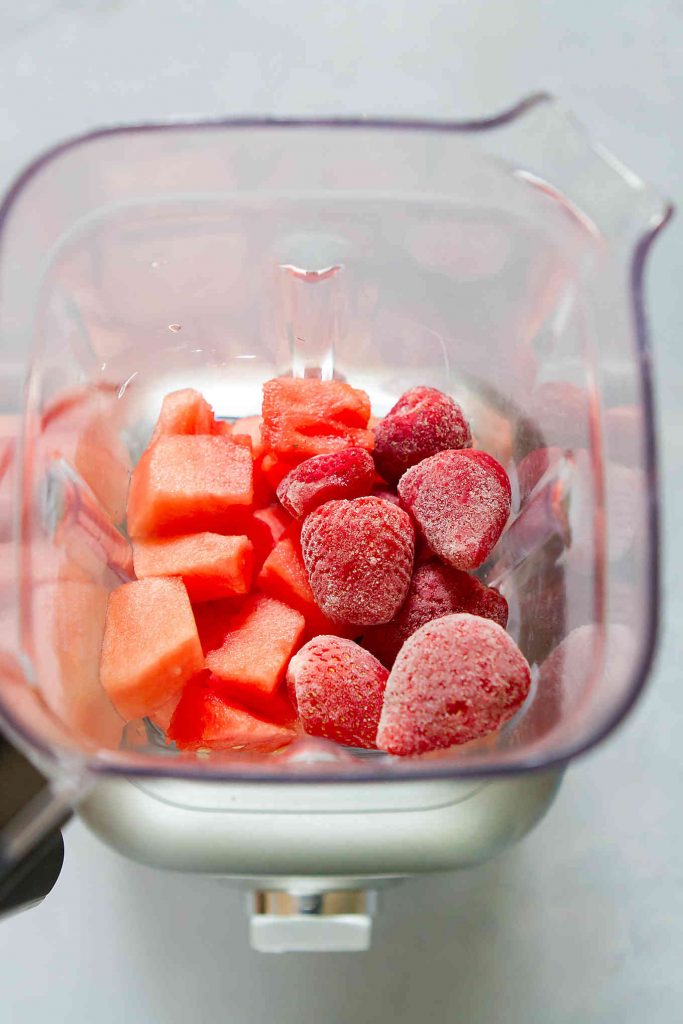 Watermelon chunks and frozen strawberries in a blender.