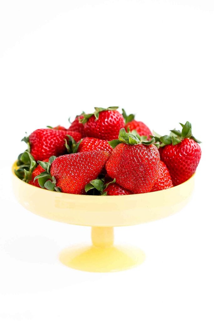 Whole strawberries in a mini yellow cake stand.