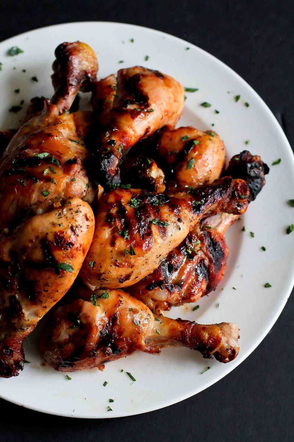 Grilled chicken drumsticks, sprinkled with parsley on a white plate.