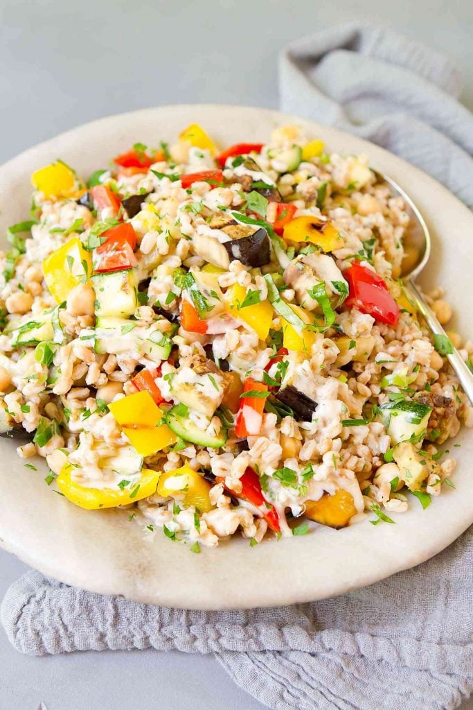 Cooked farro with grilled vegetables in a stone bowl.