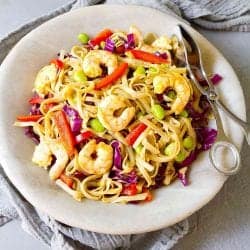 Curry noodles with shrimp and vegetables in a light gray stone bowl.