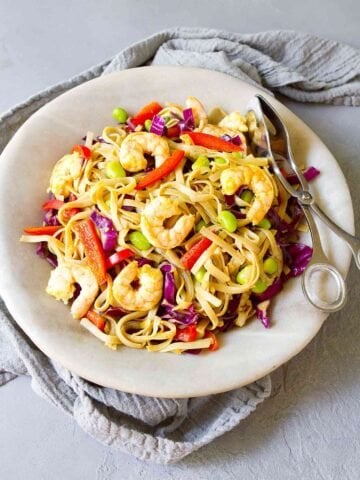 Curry noodles with shrimp and vegetables in a light gray stone bowl.
