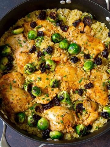 Cooked chicken thighs, quinoa and Brussels sprouts in a large nonstick skillet.