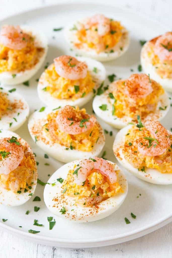 Deviled eggs with shrimp on top, sprinkled with parsley and paprika