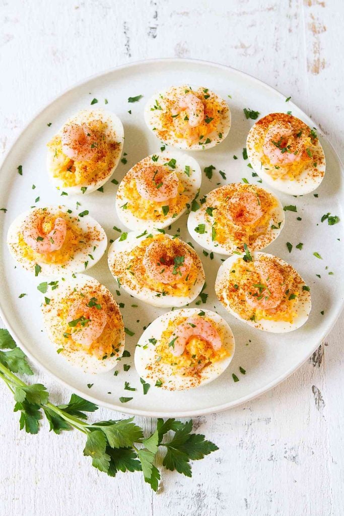 Light deviled eggs with shrimp on a white plate.