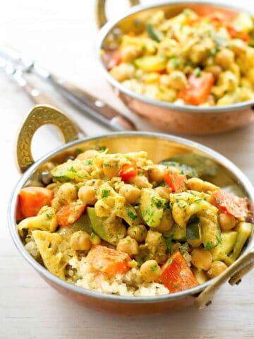 Cauliflower, zucchini and chickpea curry with quinoa in brass bowls with handles.