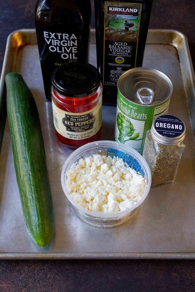 Ingredients for Mediterranean cucumber salad on a baking sheet.