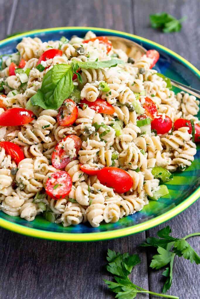 Tuna pasta salad with grape tomatoes in a blue-green bowl. 