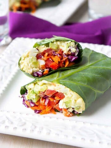 Collard green wraps filled with egg salad and vegetables, on a white plate.
