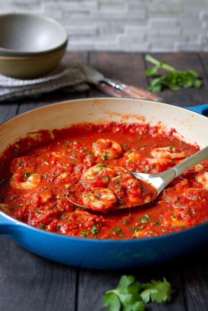Seafood tomato sauce in a large blue skillet, on wood table.
