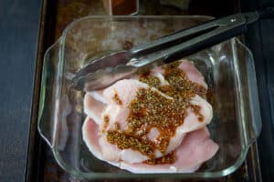 Spice rub poured over turkey cutlets in a glass dish.