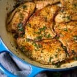 Cooked turkey cutlets with parsley in a large ceramic skillet.