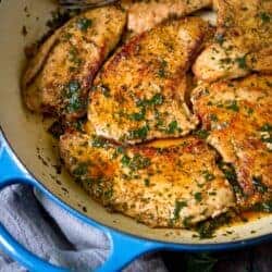 Cooked turkey cutlets with parsley in a large ceramic skillet.