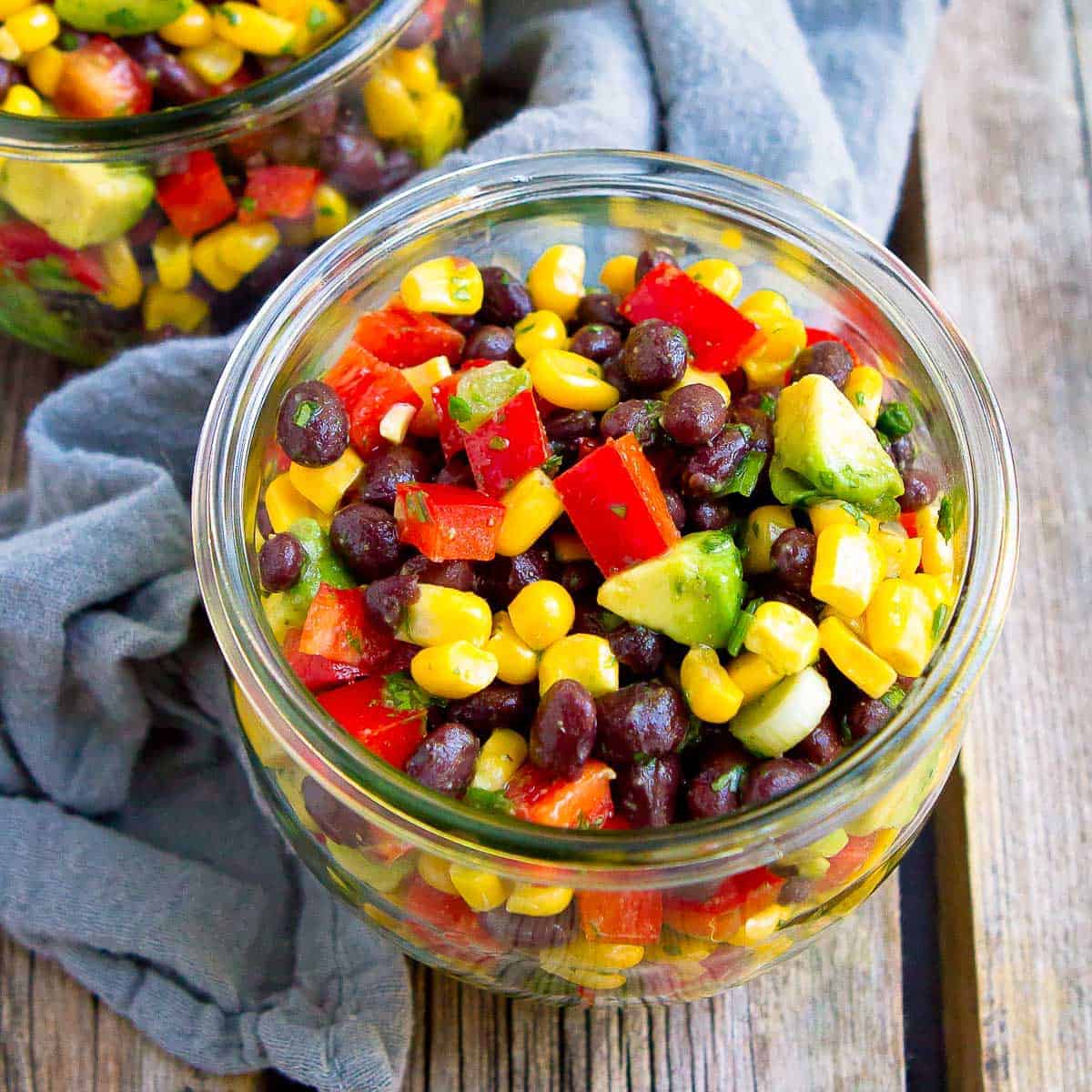 Black bean and corn salad with avocado in a glass jar.