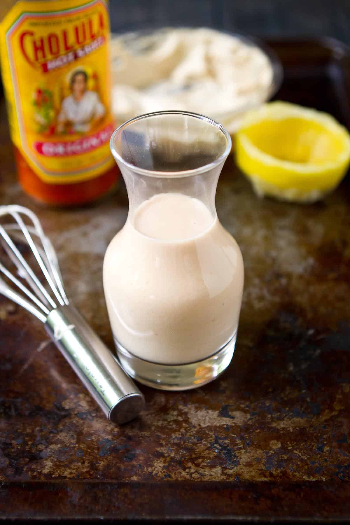 Glass carafe with salad dressing. Whisk, hot sauce and lemon on the side.
