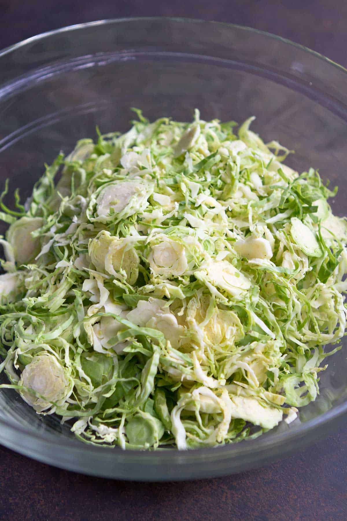 Shredded Brussels sprouts in a glass bowl.