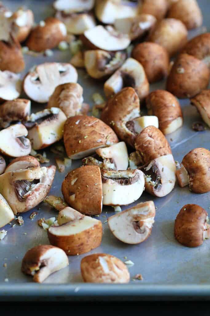 Quartered crimini mushrooms on a baking sheet
