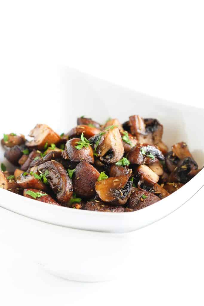 Roasted mushrooms with garlic and parsley in a white bowl.