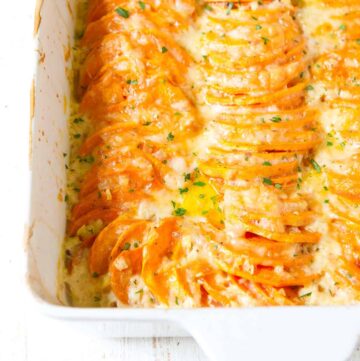 Scalloped sweet potatoes in a large white baking dish.