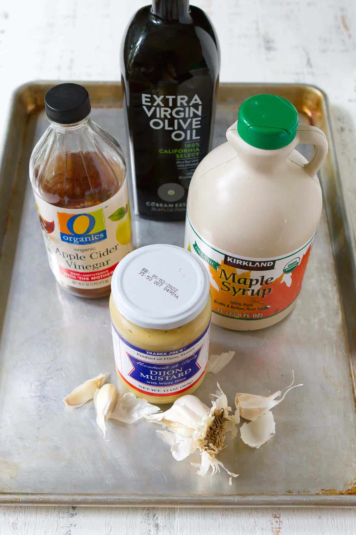 Ingredients for apple cider vinegar salad dressing on a baking sheet.