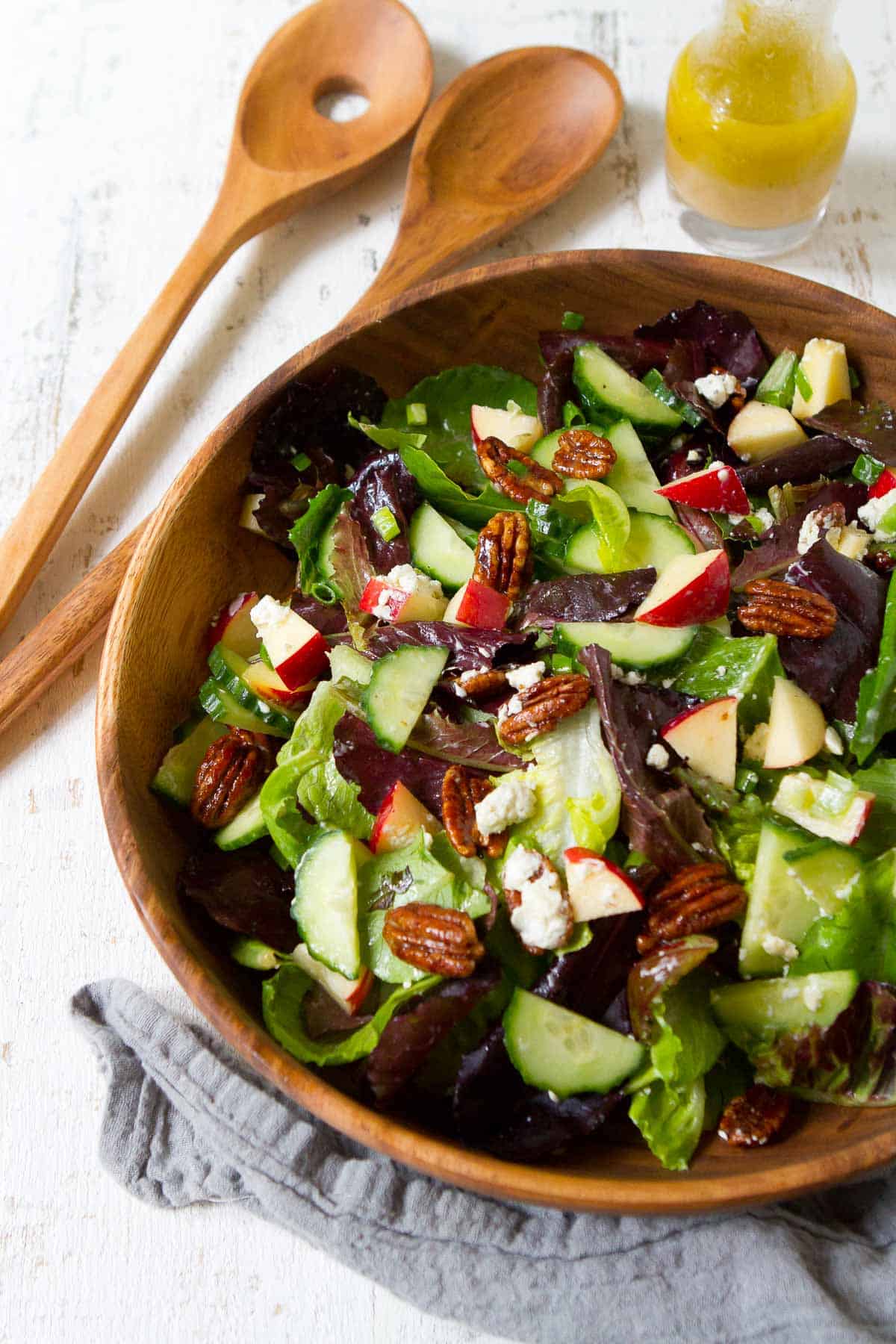 Autumn salad with pecans and apple in a wooden salad bowl.