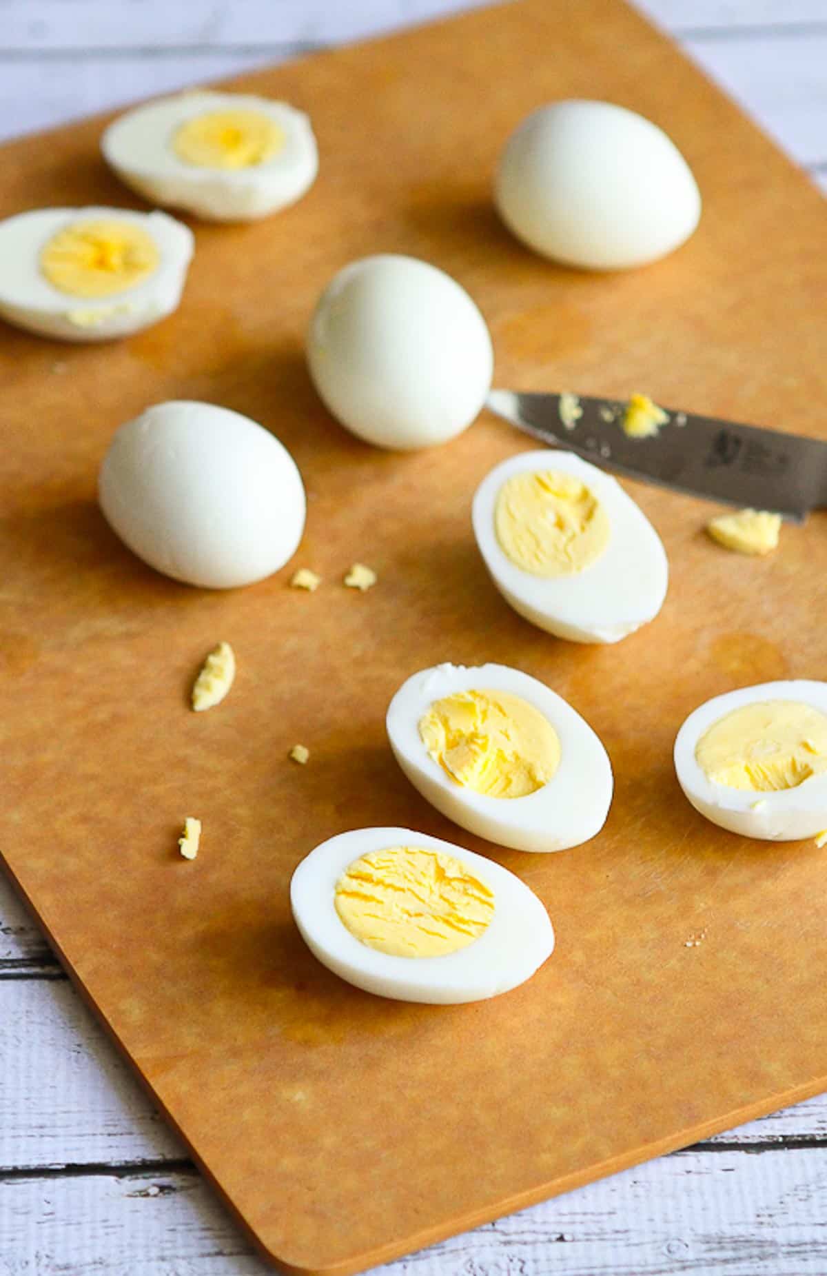 Hard boiled egg halves and knife on a cutting board.