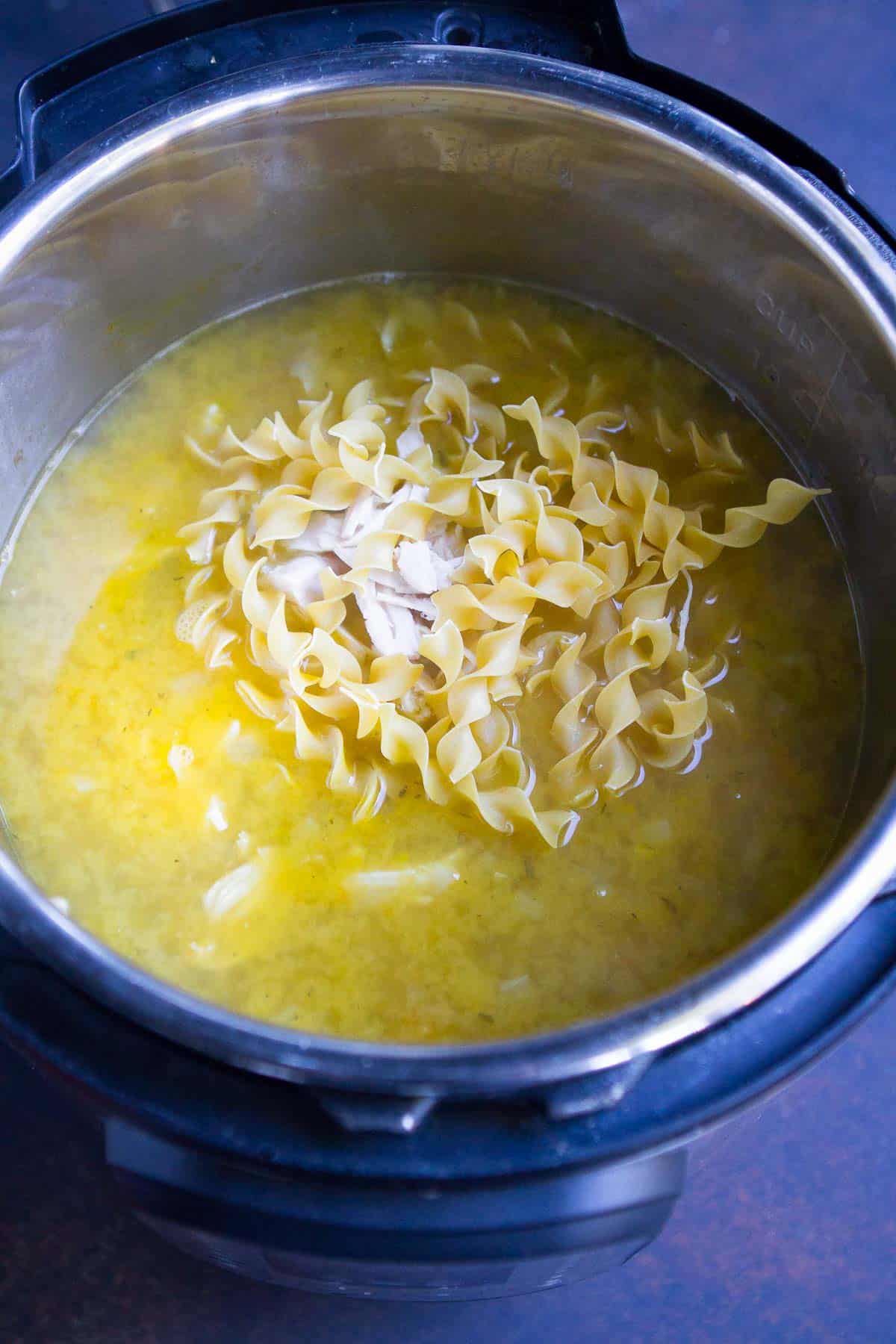 Broth and egg noodles in a pressure cooker.