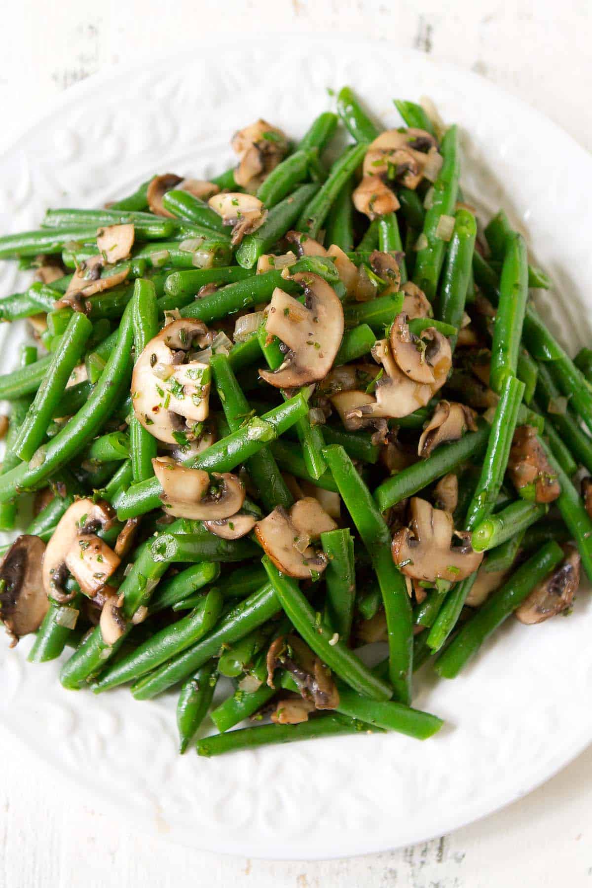 Sautéed green beans and mushrooms on a white plate.