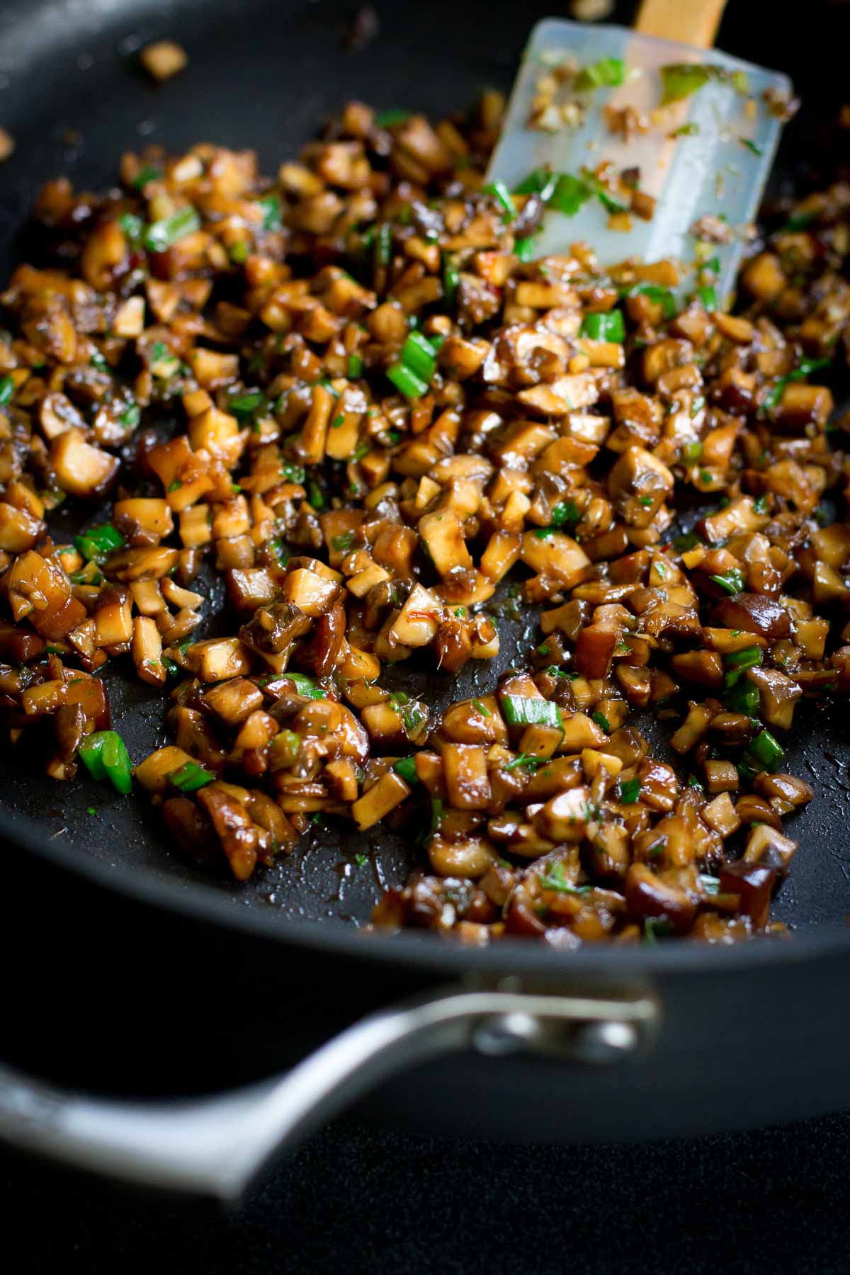 Cooked diced mushrooms with hoisin sauce and green onions in a large skillet.