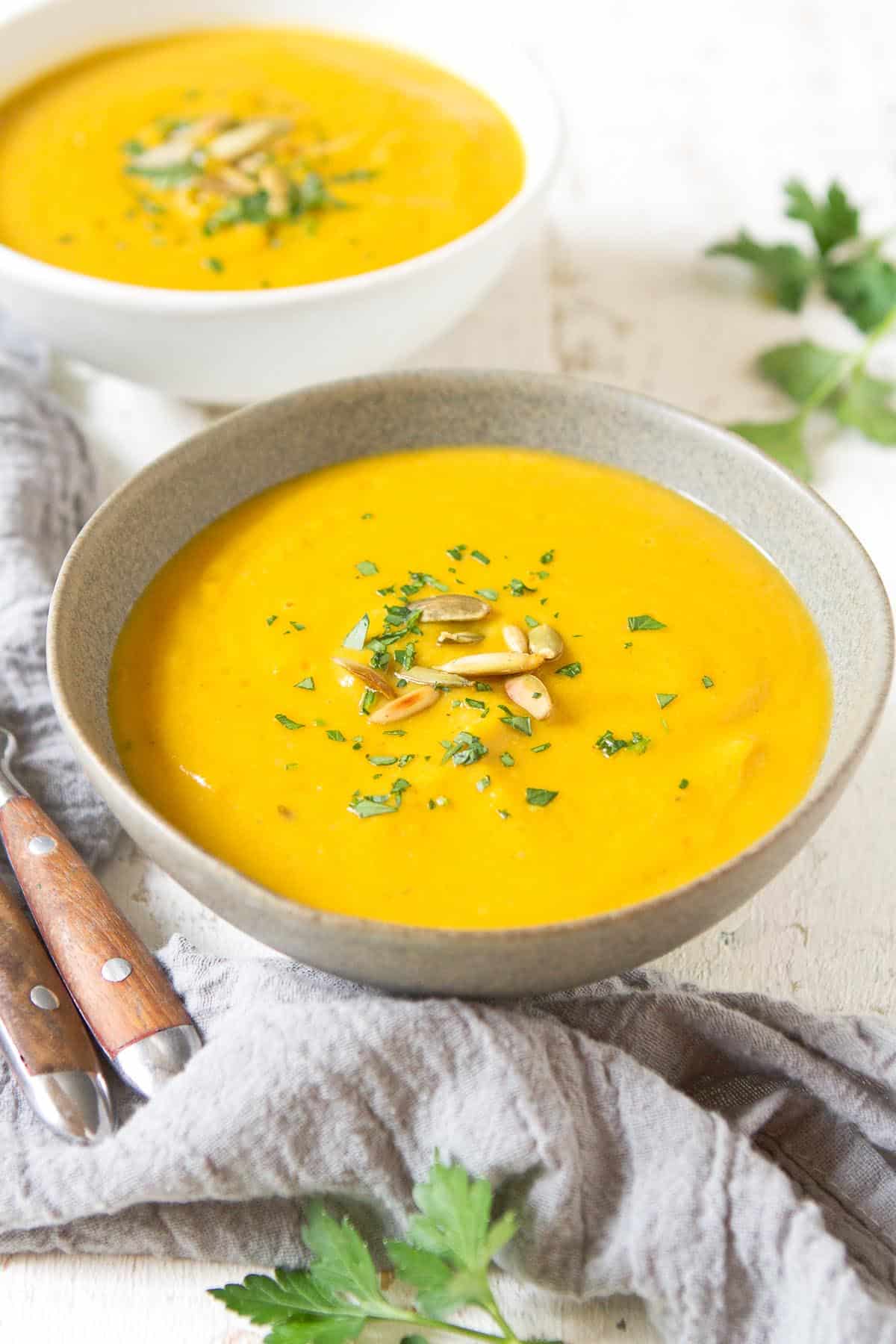 Light gray and white bowls filled with healthy cauliflower soup. Spoons on the side.