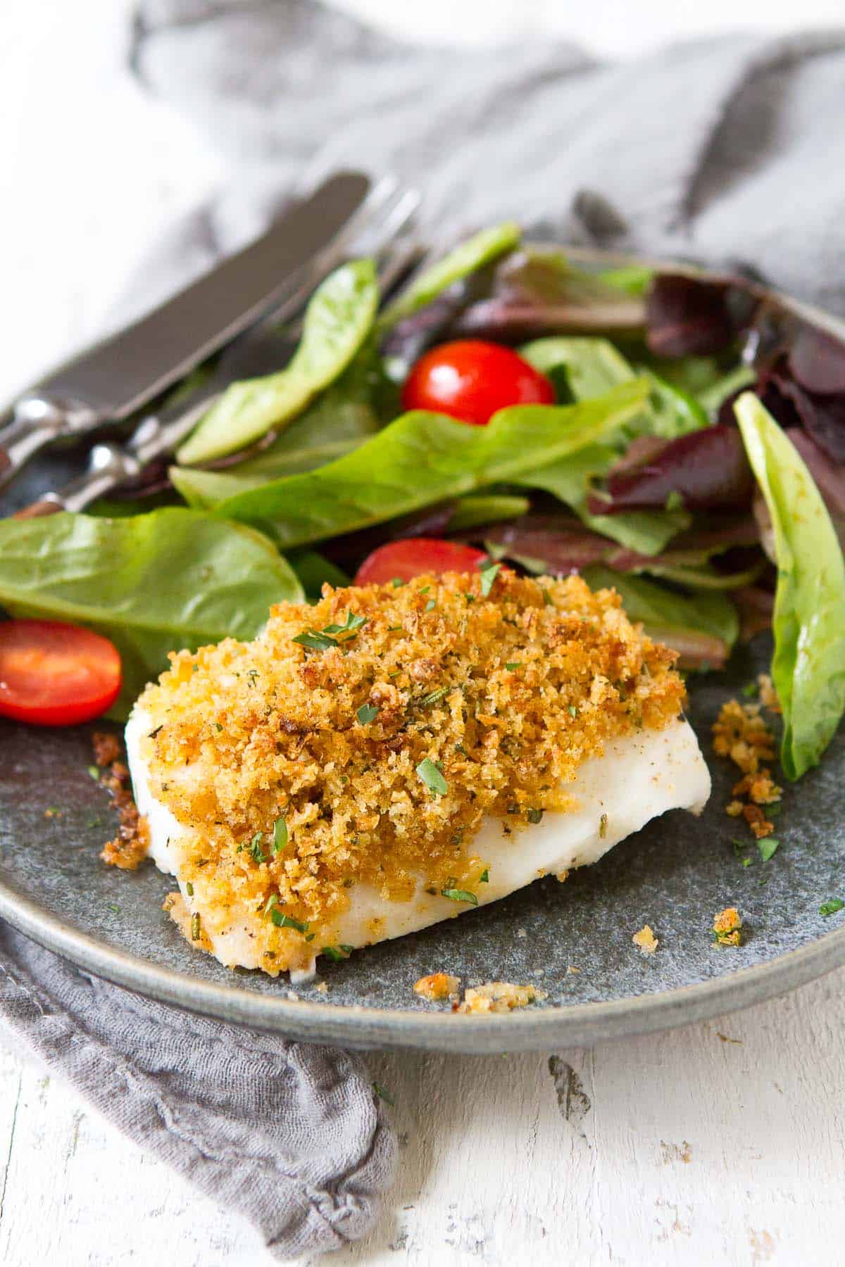 Panko-topped baked fish on a gray plate, with a green salad.
