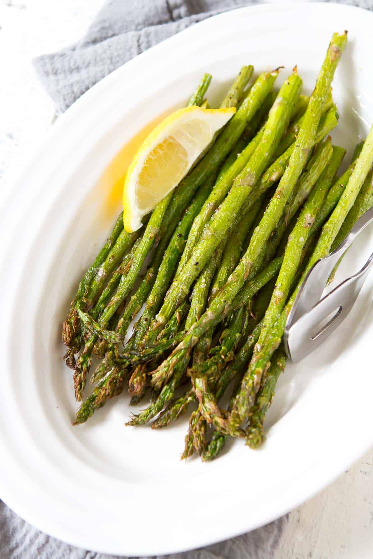 Stalks of air fried asparagus on a white serving plate.
