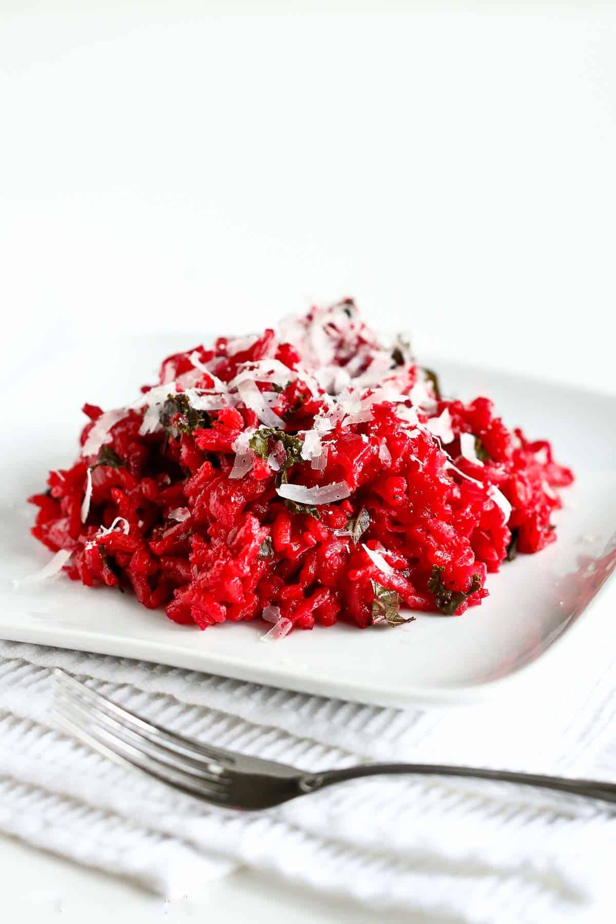 Beetroot risotto with bit of kale mixed in on a white plate.