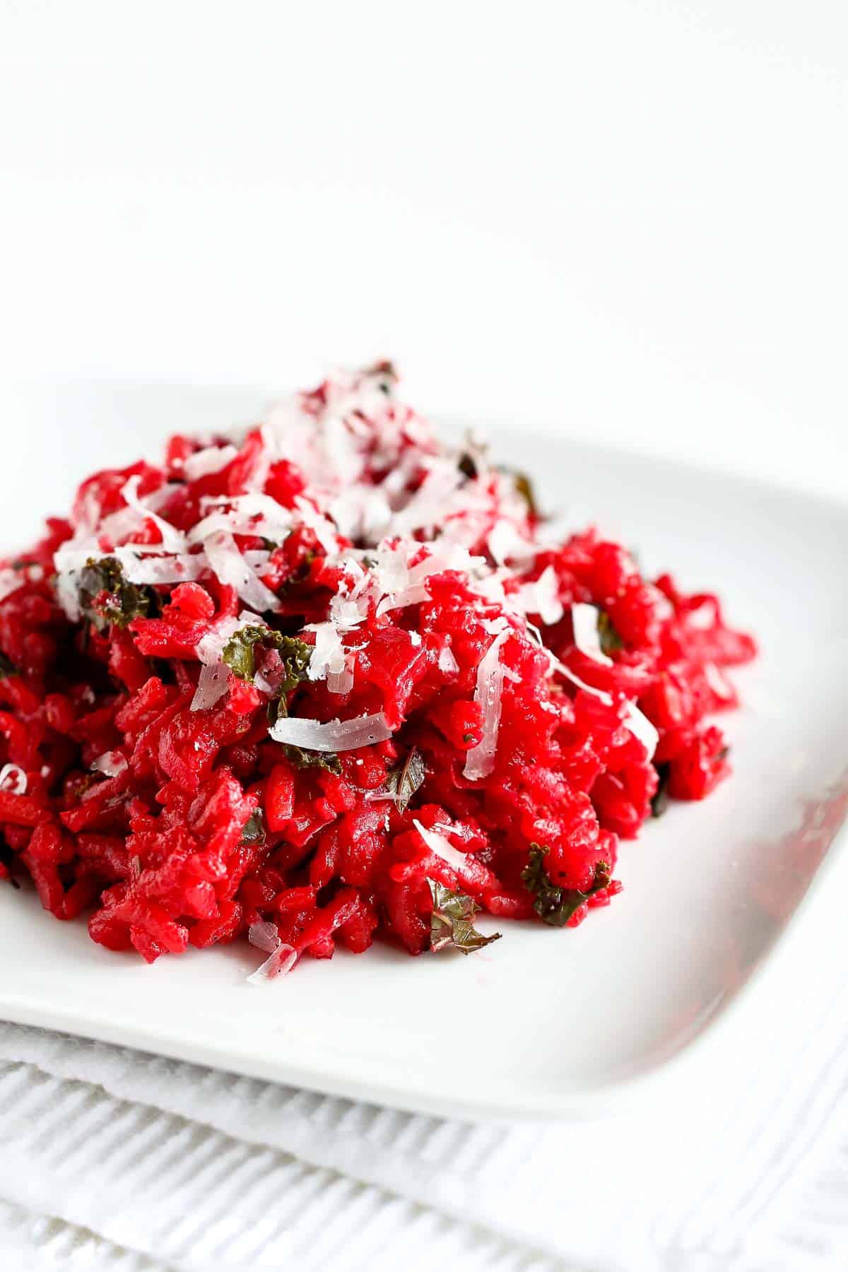 Beet risotto with kale on a white plate.