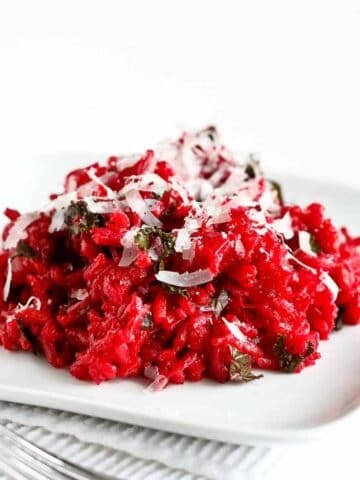Beet risotto with kale on a white plate.