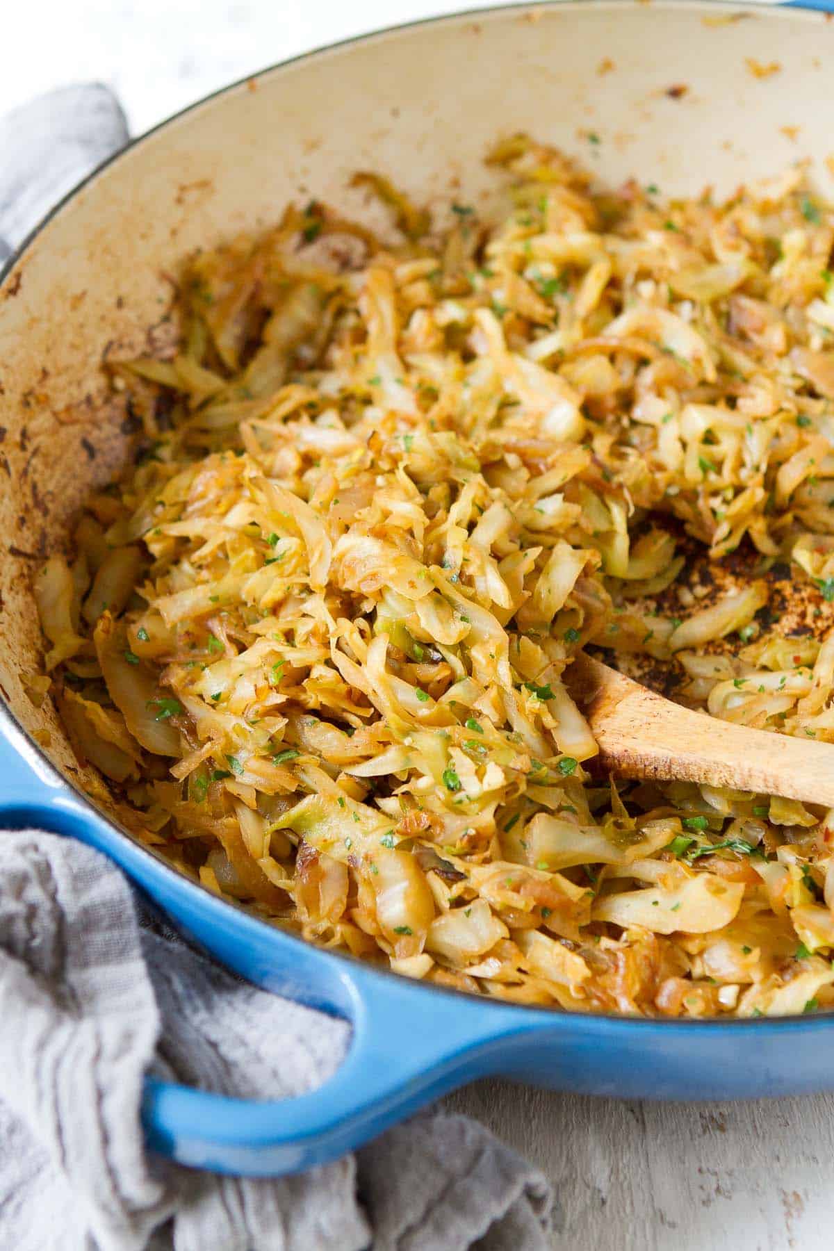 Caramelized cabbage and onions in a large blue braiser pan.